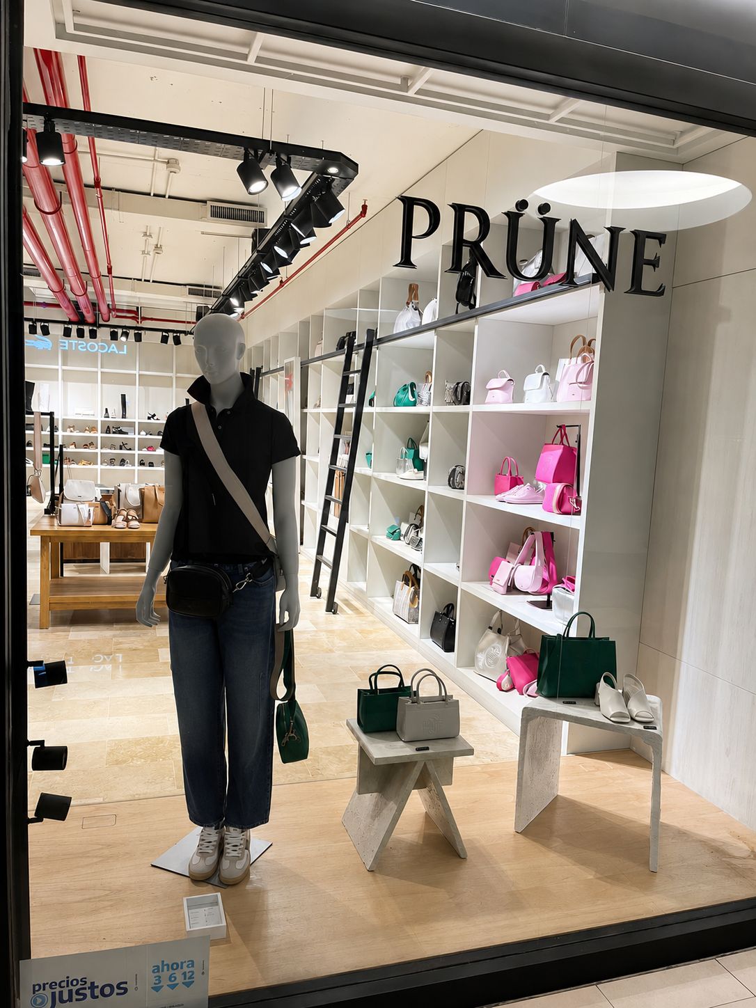 Sucursal PRÜNE construida por NEST — vidriera con exhibidores de carteras y calzado