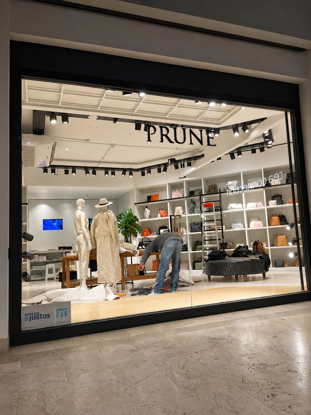 Sucursal PRÜNE construida por NEST — vidriera en montaje final con exhibidores de carteras