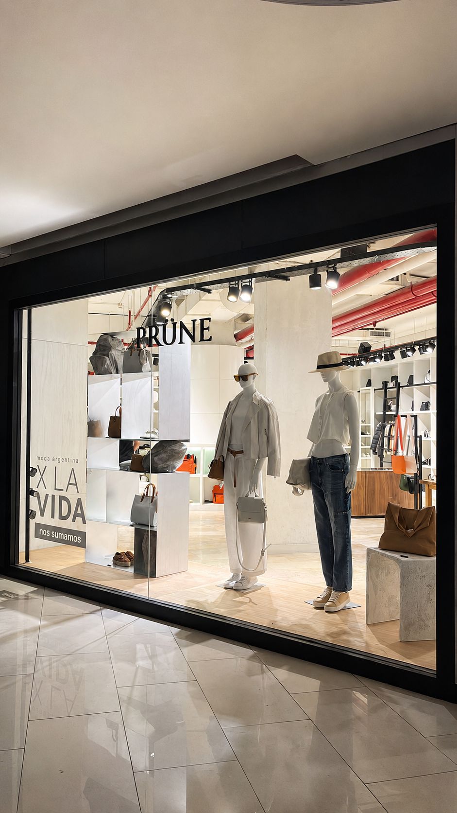 Sucursal PRÜNE construida por NEST — vidriera con maniquíes y ambientación de temporada